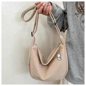Detail of beige corduroy dumpling bag featuring adjustable strap and cute dog charm