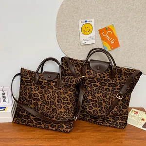Dettaglio di borse leopardate in due dimensioni con manici in pelle marrone e dettagli oro