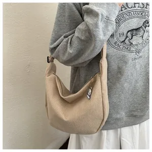 Detail of beige corduroy crescent bag showing textured fabric and cloud charm decoration
