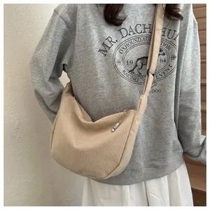 Detail of a beige corduroy crescent crossbody bag showing soft texture and wide strap