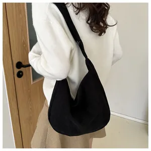 Detailed view of black corduroy hobo bag on shoulder showing texture and slouchy design