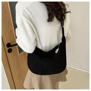 Detail of black corduroy crossbody bag texture and crescent shape on a shoulder