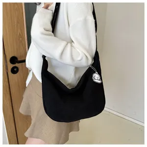Detail of black corduroy crossbody bag with adjustable strap and cute dog charm decoration