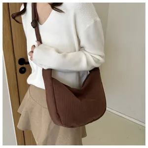 Detail of coffee brown corduroy crescent bag showing ribbed texture and adjustable strap