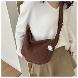 Detail of brown corduroy crescent bag featuring texture and a cute puppy keychain