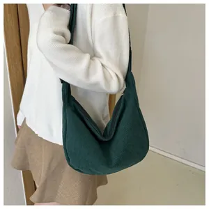 Detailed texture of dark green corduroy fabric on a minimalist crossbody crescent bag