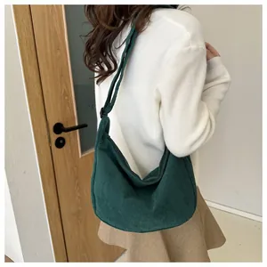 Detail of dark green corduroy dumpling bag with adjustable strap worn with casual outfit
