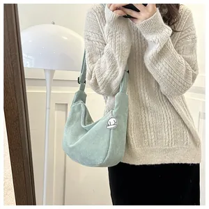 Close-up of mint green corduroy crescent crossbody bag with cute cloud pendant on strap