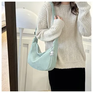 Mint green corduroy half moon crossbody bag worn by a model in a cozy indoor setting