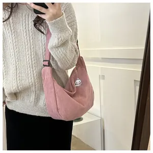 Detail of pink corduroy crossbody bag with adjustable strap and cute cartoon pendant