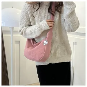 Detail view of pink corduroy crescent bag featuring a cute white puppy pendant