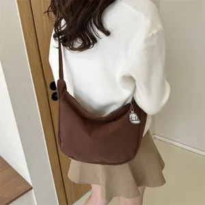 Brown corduroy crescent shoulder bag with dog pendant shown on model back view