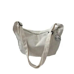 Minimalist cream corduroy crescent crossbody bag with cute white puppy pendant detail