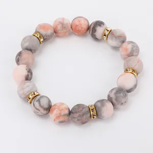 Macro detail of 8mm pink zebra stone beads and gold rhinestone spacers on elastic bracelet