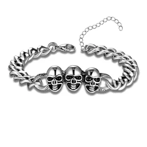Punk silver Cuban link bracelet featuring triple skull charms and lobster clasp closure