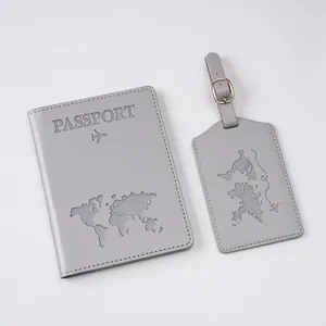 Close-up of gray passport cover and luggage tag set with embossed world map and text