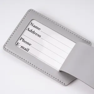 Detailed close-up of grey leather luggage tag with clear PVC window and ID card insert