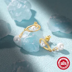 Detail of S925 sterling silver planet earrings with gold plating and hanging pearls