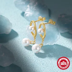 Macro shot of S925 sterling silver pearl drop earrings on a light blue stone base