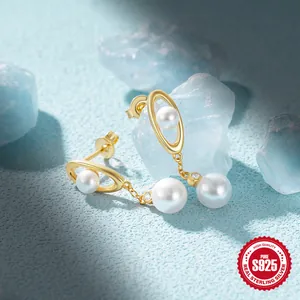 Detailed shot of golden Saturn-shaped earrings with pearls and S925 sterling silver stamp