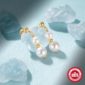 Macro view of S925 sterling silver pearl earrings with gold chain and dual beads