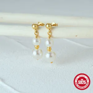 Close-up of S925 sterling silver drop earrings with white pearls on a branch