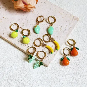 Detail shot of assorted fruit pendant earrings on stone surface with summer vibe