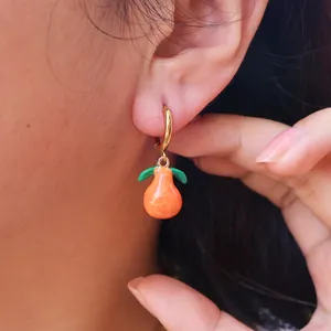 Golden hoop earrings with vibrant orange fruit charms and green leaves for a summer look