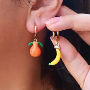 Detailed close-up of asymmetrical lemon and banana drop earrings with gold finish