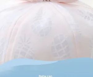 Detail of light pink baby sun hat featuring white pineapple prints and a cute bow
