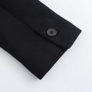 Detail shot of black wool coat cuff with a polished button and textured fabric
