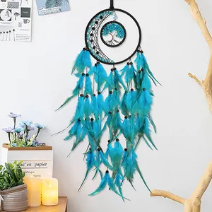 Blue dreamcatcher with tree of life stones and feathers hanging on a white wall
