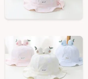 Detail of cotton baby sun hats in pink, beige, and blue with fruit leaf decor