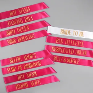 Close-up of pink and white satin bachelorette party sashes with gold Bride to Be lettering