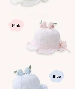 Detail of pink and blue baby sun hats featuring apple heart decor and bow ties