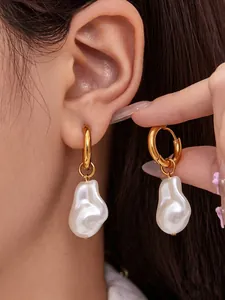 Detailed close-up of 18k gold hoop earrings with large baroque pearls on a model