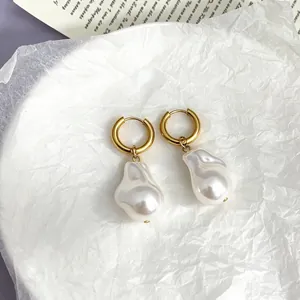 Detail of 18k gold plated hoop earrings with white baroque pearls on a minimalist background