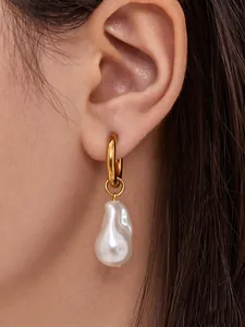 Close-up of a large baroque pearl earring with 18k gold hoop on model's ear
