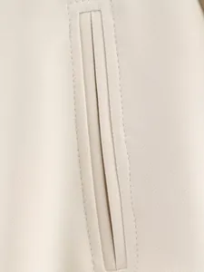 Vue macro d'une poche passepoilée sur une veste beige montrant des coutures de qualité