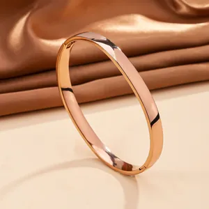 Polished rose gold stainless steel oval bangle shown on elegant silk background