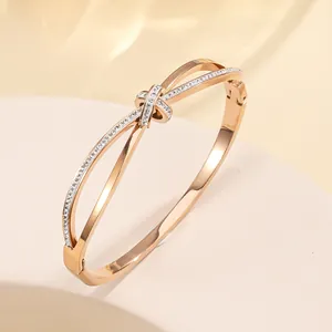 Detail of rose gold titanium bangle with crossover knot design and white pavé crystals
