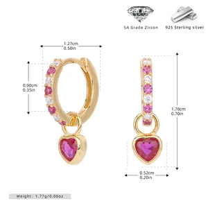 Detail view of gold 925 silver hoop earrings with pink zircons and heart pendants