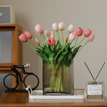 Close-up of pink tulip bouquet in a grey ribbed glass vase on a white tray