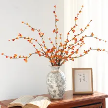 Blue floral ceramic vase with decorative orange berry branches on a wooden table