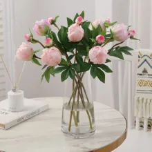 Detailed view of pink silk peony bouquet in a glass vase on a marble tabletop