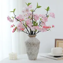 Pink tulip bundle in a rustic white ceramic vase on a minimalist white tabletop setting