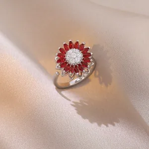 Detailed close-up of a rotating sunflower ring with red and white zircons on silk