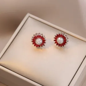 Close-up of sunflower stud earrings with red marquise gems and micro-pave crystals