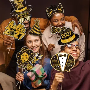 Group of friends using black and gold 2027 New Year photo booth props at a festive party