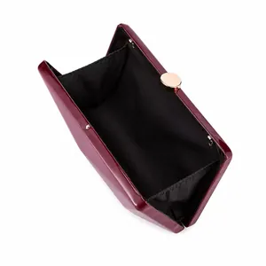 Top view of open burgundy patent leather clutch bag with gold clasp and black fabric interior